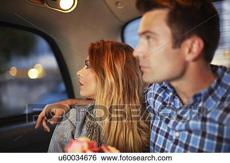 Couple looking out of city taxi window at night View Large Photo Image Stock Photograph - Couple looking out of city taxi window at night. Fotosearch