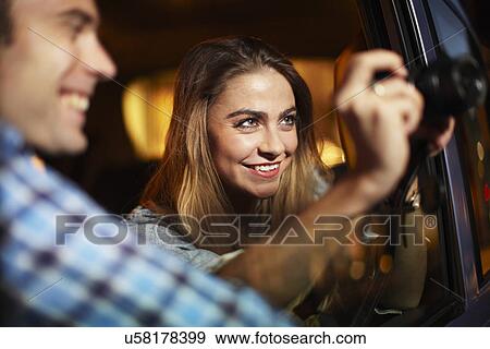 Couple photographing out of city taxi window at night View Large Photo Image Stock Photo - Couple photographing out of city taxi window at night. Fotosearch