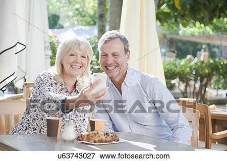 Stock Photo - Couple taking selfie with smartphone at cafe. Fotosearch