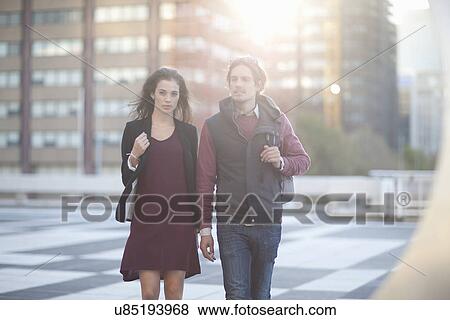 Stock Photo - Couple walking across rooftop parking lot in city. Fotosearch