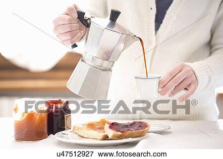 Stock Photo - Cropped shot of young woman pouring coffee for breakfast. Fotosearch