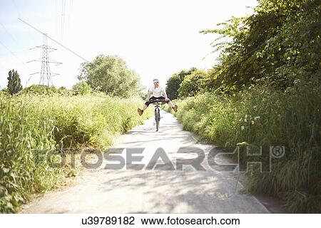 Cyclist cycling on path View Large Photo Image Stock Image - Cyclist cycling on path. Fotosearch