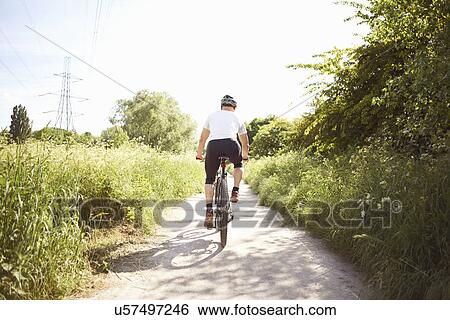 Cyclist cycling on path View Large Photo Image Stock Photograph - Cyclist cycling on path. Fotosearch