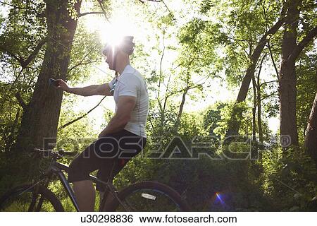 Stock Photograph - Cyclist stopping for break in forest. Fotosearch