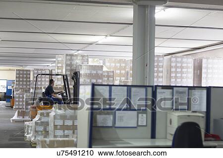 Stock Image - Factory worker using forklift truck. Fotosearch