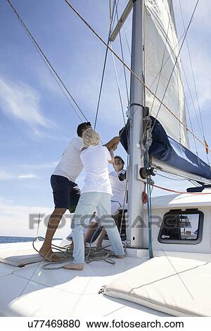 Stock Image - Father and brothers hauling sail on catamaran near Fuerteventura, Spain. Fotosearch