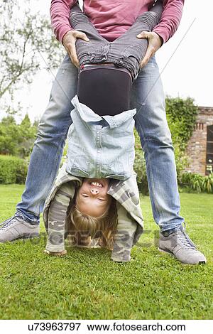 Stock Photo - Father holding daughter upside down. Fotosearch