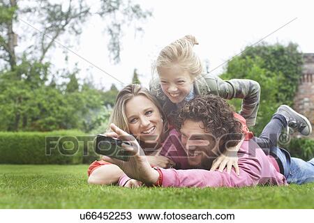 Father photographing family lying on lawn View Large Photo Image Stock Image - Father photographing family lying on lawn. Fotosearch