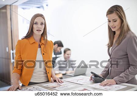 Stock Image - Female colleagues working in office. Fotosearch