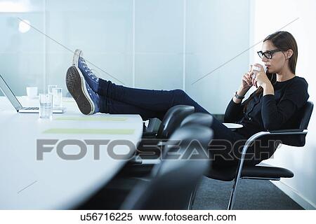 Female office worker drinking coffee with feet up on conference table View Large Photo Image Stock Photography - Female office worker drinking coffee with feet up on conference table. Fotosearch