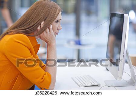 Female office worker staring at computer screen View Large Photo Image Stock Photography - Female office worker staring at computer screen. Fotosearch