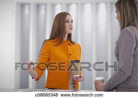 Stock Photo - Female office worker wearing orange jacket talking. Fotosearch