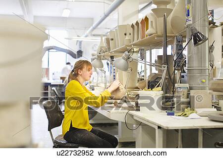 Stock Image - Female potter working in ceramic workshop. Fotosearch