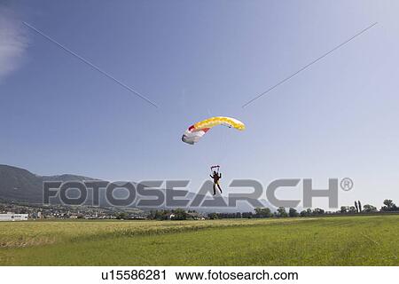Stock Image - Female skydiver parachuting into field, approaching the landing zone, Grenchen, Berne, Switzerland. Fotosearch