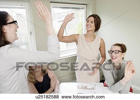 Four businesswomen celebrating with high fives in conference room View Large Photo Image Stock Photo - Four businesswomen celebrating with high fives in conference room. Fotosearch