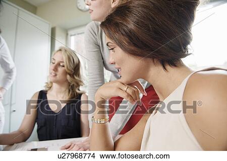 Picture - Four businesswomen looking at blueprint designs in office. Fotosearch