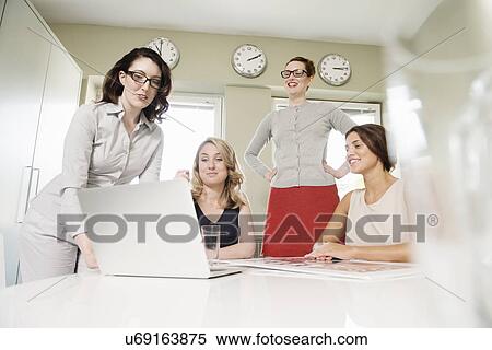 Stock Photography - Four businesswomen looking at laptop. Fotosearch