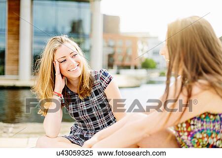 Stock Photography - Friends chatting by canal. Fotosearch