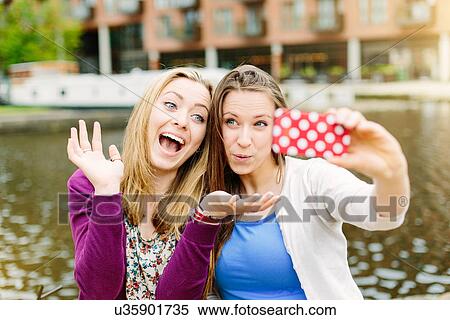 Stock Photography - Friends taking selfie by canal. Fotosearch