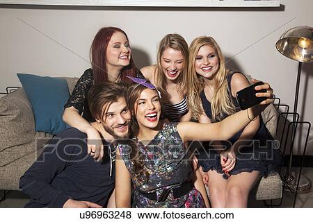 Stock Photo - Friends taking selfie on sofa. Fotosearch