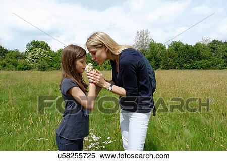 Girl and her mother smelling wildflowers in field View Large Photo Image Stock Photography - Girl and her mother smelling wildflowers in field. Fotosearch