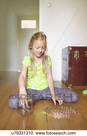 Stock Image - Girl counting coins from savings jar. Fotosearch