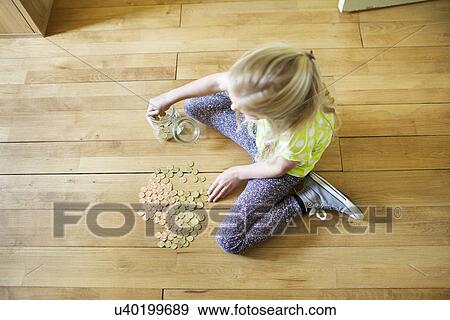 Stock Photo - Girl counting coins from savings jar. Fotosearch