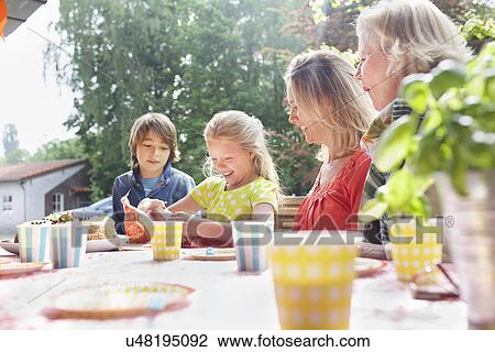 Girl opening birthday gift with her family at birthday party View Large Photo Image Stock Image - Girl opening birthday gift with her family at birthday party. Fotosearch