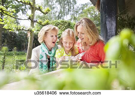 Stock Photograph - Girl opening jar of coins with family. Fotosearch
