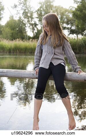 Girl sitting on wooden fence looking down at lake View Large Photo Image Stock Photograph - Girl sitting on wooden fence looking down at lake. Fotosearch