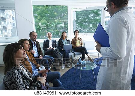 Group of people sitting, looking at man in labcoat View Large Photo Image Stock Image - Group of people sitting, looking at man in labcoat. Fotosearch