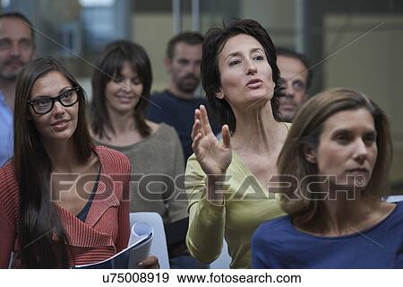 Stock Photo - Group watching presentation, woman raising hand. Fotosearch