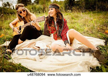 Hippy girls on blanket in field, playing guitar View Large Photo Image Picture - Hippy girls on blanket in field, playing guitar. Fotosearch