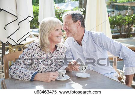 Stock Photography - Husband whispering to wife at cafe. Fotosearch