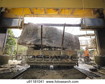 Stock Image - Large rock being cut in stone saw in quarry. Fotosearch
