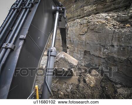 Stock Image - Large rock in bucket of excavator in stone quarry. Fotosearch
