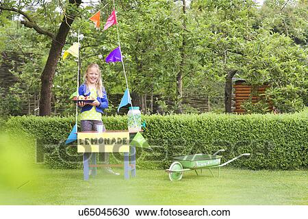 Stock Image - Lemonade stand girl with tray of apples behind her stand. Fotosearch