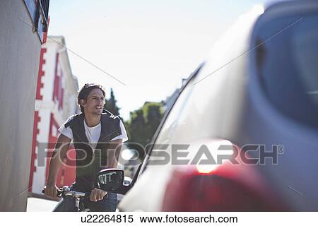 Stock Photography - Low angle view of mid adult male cyclist in city. Fotosearch