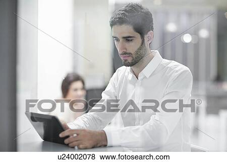 Stock Photo - Male office worker using digital tablet. Fotosearch