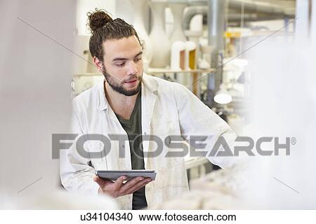 Stock Image - Male potter using digital tablet in ceramic workshop. Fotosearch