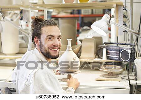 Stock Image - Male potter working on vase in ceramic workshop. Fotosearch
