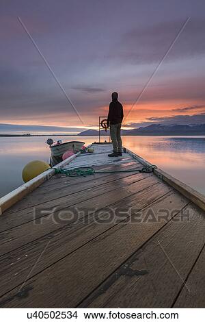 Man gazing from pier at sunset, Hvalfjordur, Iceland View Large Photo Image Picture - Man gazing from pier at sunset, Hvalfjordur, Iceland. Fotosearch