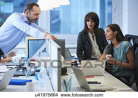 Man leaning over screen partition, speaking to colleagues View Large Photo Image Picture - Man leaning over screen partition, speaking to colleagues. Fotosearch