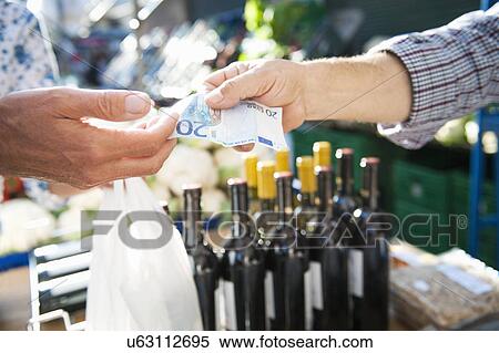 Stock Photography - Man paying for wine at market. Fotosearch