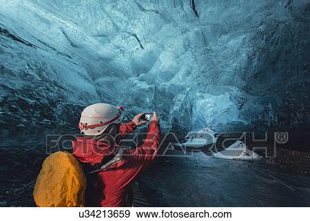 Stock Photo - Man photographing ice cave with smartphone, Vatnajokull Glacier, Vatnajokull National Park, Iceland. Fotosearch