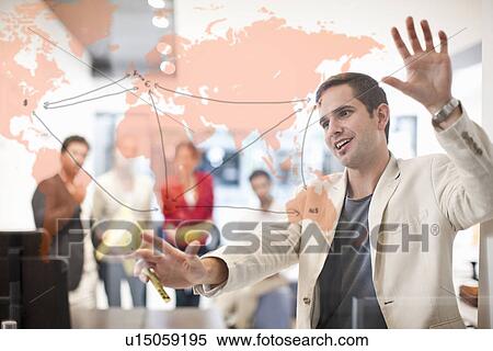 Stock Photography - Man writing on glass screen, colleagues watching. Fotosearch