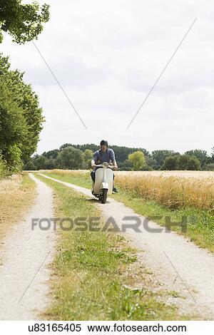 Mature man riding motor scooter along dirt track with daughter holding onto waist View Large Photo Image Stock Photography - Mature man riding motor scooter along dirt track with daughter holding onto waist. Fotosearch