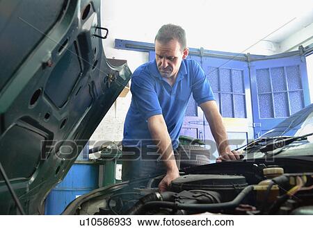 Stock Image - Mechanic checking car engine. Fotosearch