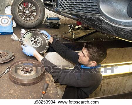 Mechanic checking disc of wheel underneath car View Large Photo Image Picture - Mechanic checking disc of wheel underneath car. Fotosearch