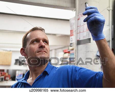 Mechanic checking spark plug View Large Photo Image Stock Photography - Mechanic checking spark plug. Fotosearch